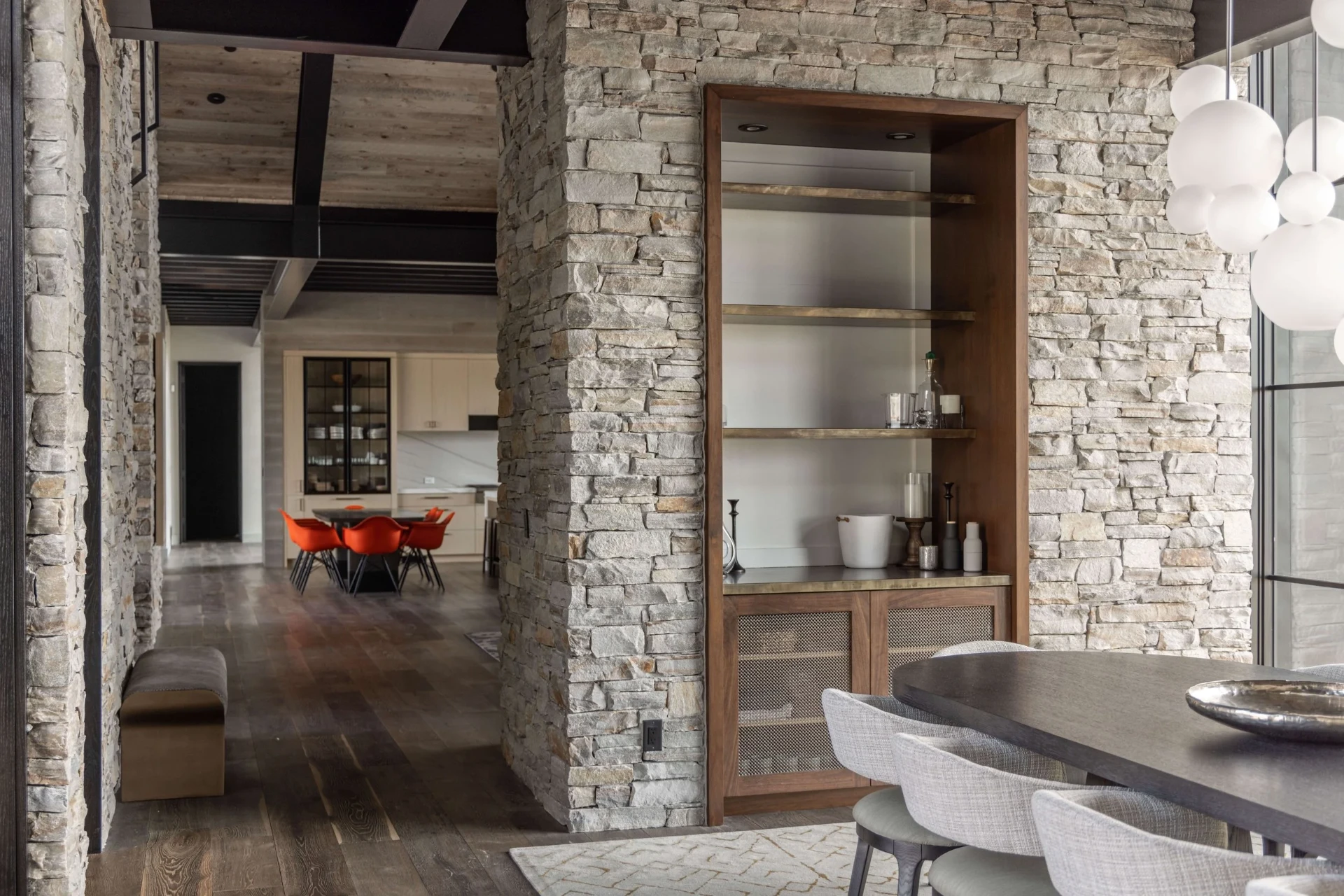 Nox wide plank European oak flooring running past a stone pier with a walnut bar niche — Ridgeview project